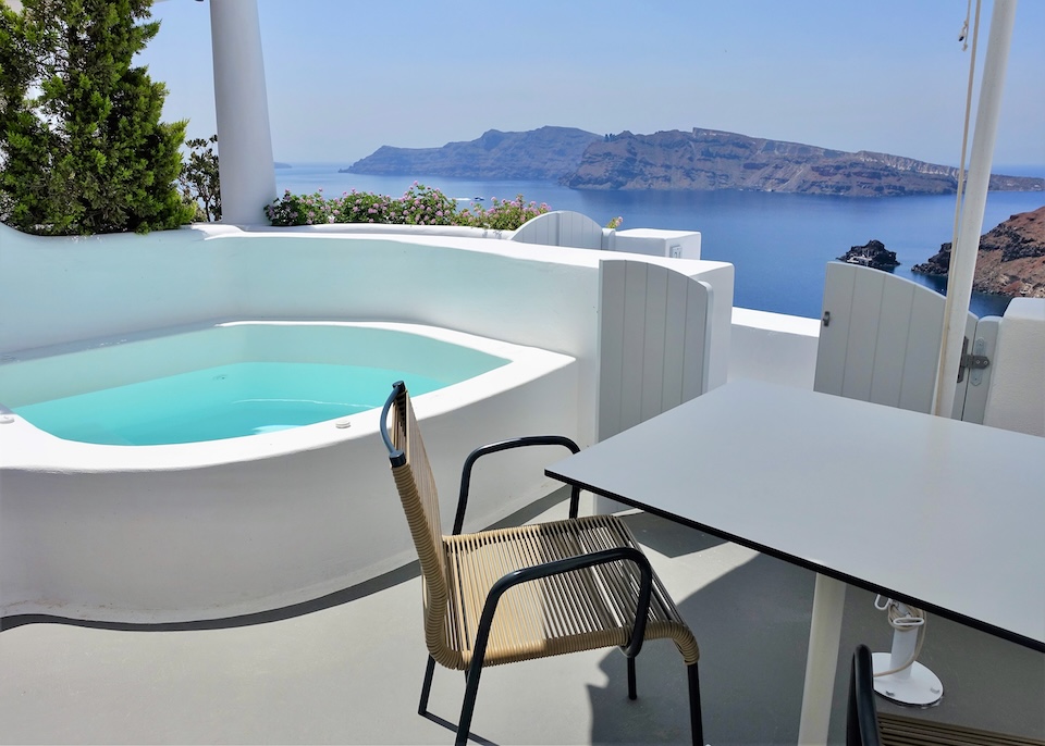 A private jacuzzi on a covered terrace overlooking the caldera and Thirassia Island at Katikies Hotel in Oia, Santorini.