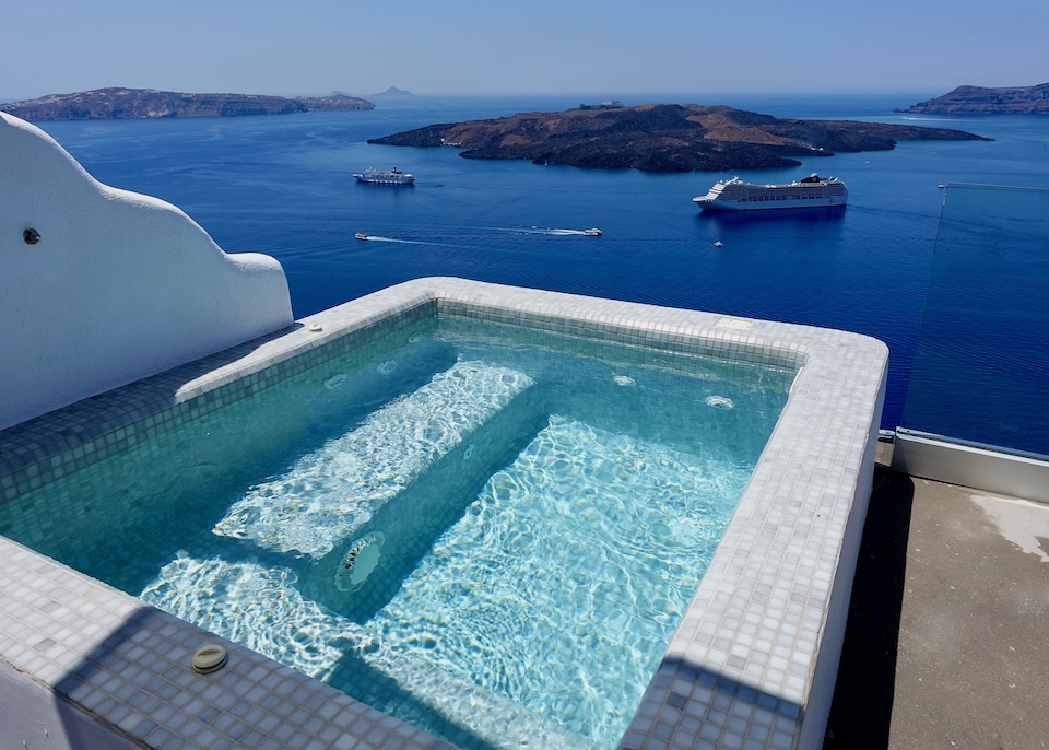 A jacuzzi made with tiles overlooking the caldera and volcano with several types of boats at Keti Hotel in Fira, Santorini.