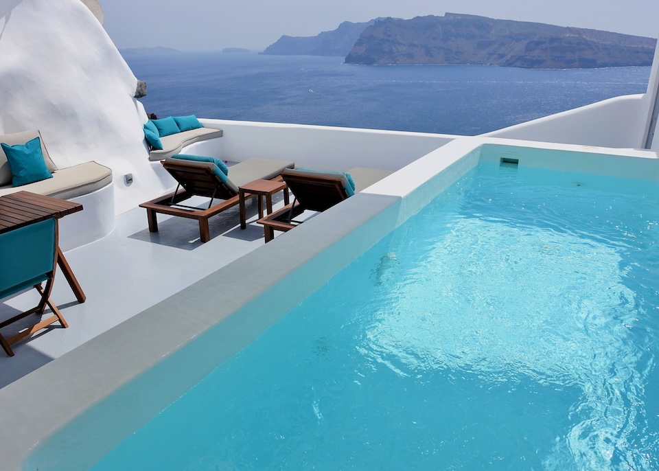 A private plunge pool on a furnished terrace above Ammoudi Bay facing Thirassia Island at Maregio Suites in Santorini.