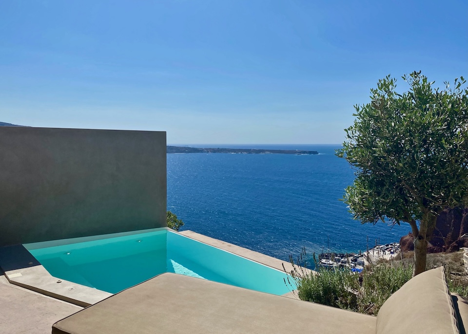 An infinity plunge pool over the caldera with an olive tree at Old Castle Oia hotel in Santorini.