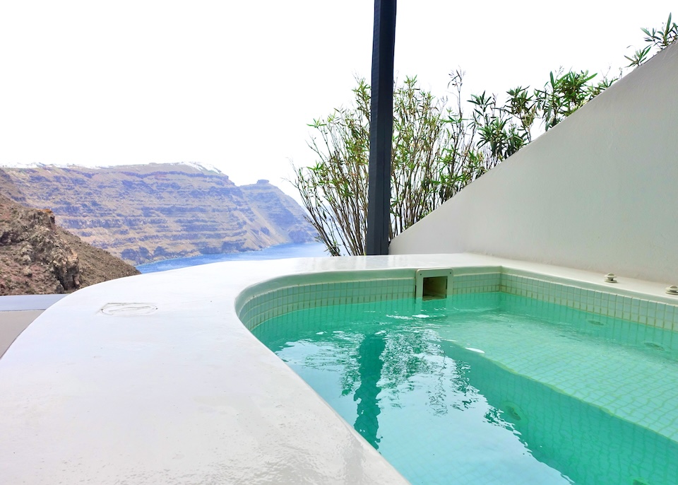 A jacuzzi with a wide edge with a side view toward above the caldera toward Imerovigli village and Skaros Rock at San Antonio hotel in Imerovigli, Santorini.