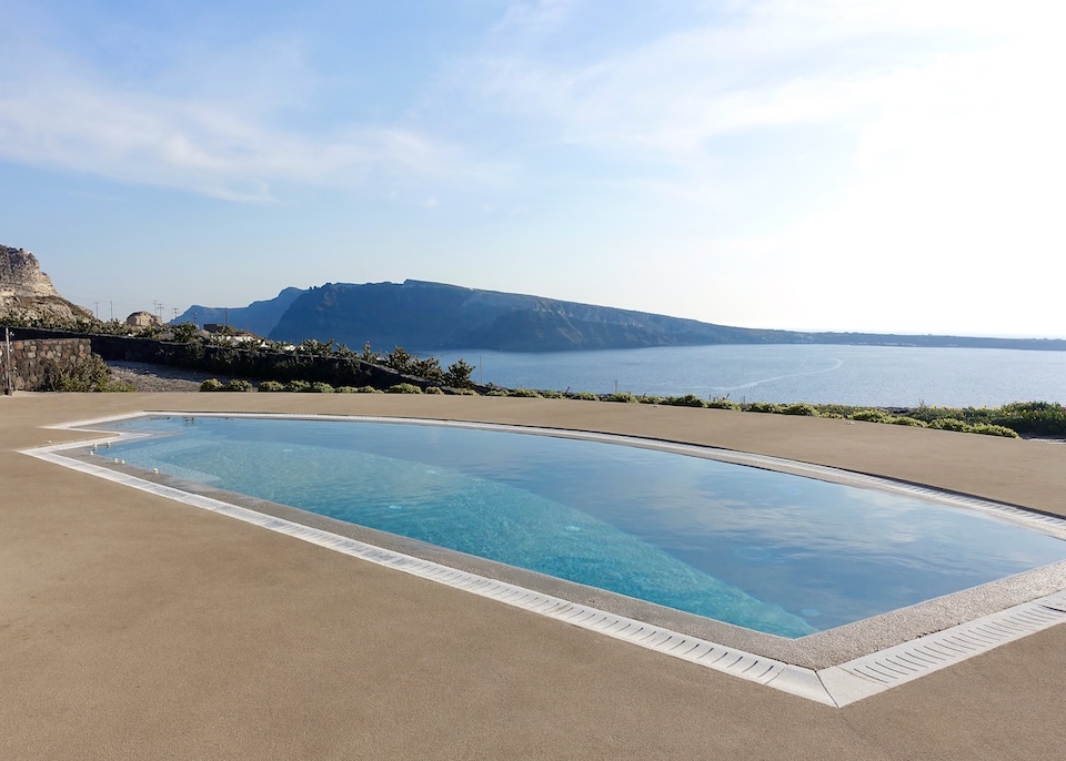 A large private pool with a west-facing view over the sea with Thirassia Island in the background at Santo Pure in Oia, Santorini