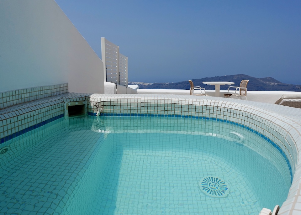 A white tile jacuzzi on a spacious private terrace facing the caldera and Oia village at White hotel in Imerovigli, Santorini.