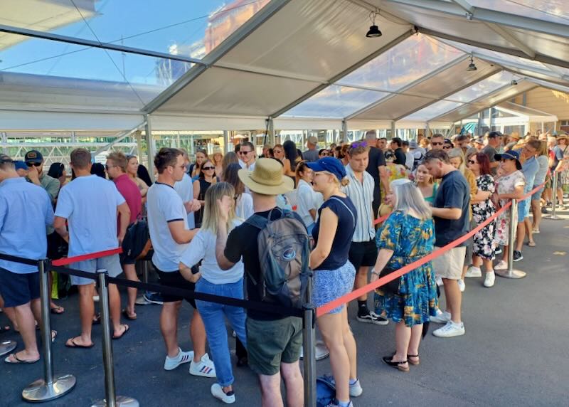 People wait in a line following a snaking roped area.