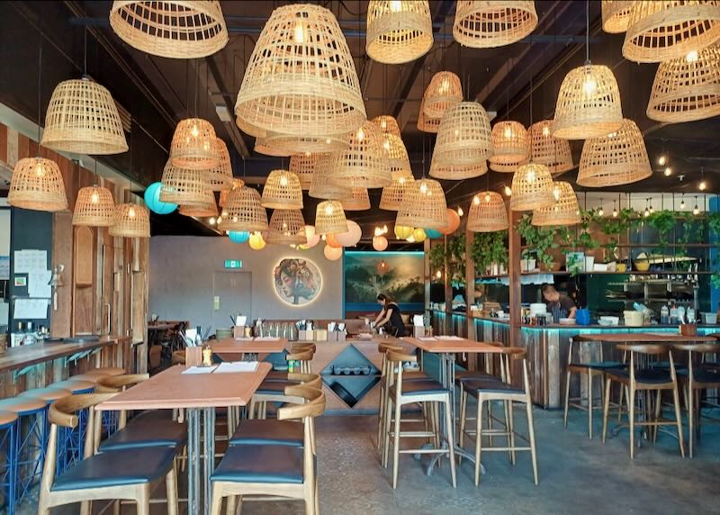 A restaurant with hanging baskets and wood chairs.