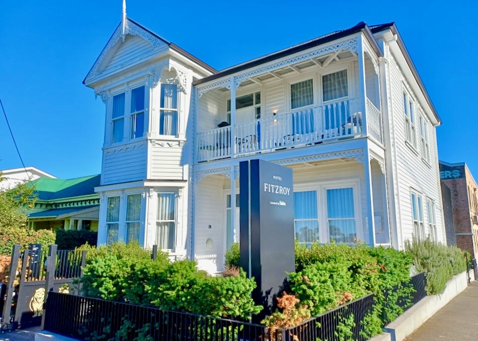 An old house with green bushes has a sign that reads, "Fitzroy."