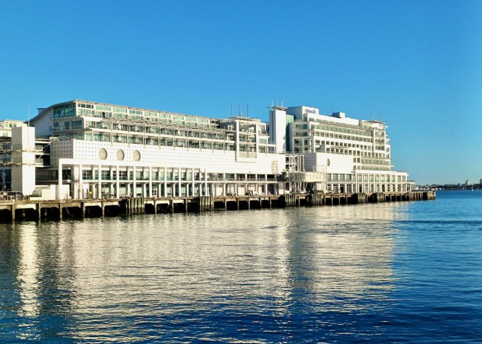 A white hotel with lots of windows sits on a pier in the water.