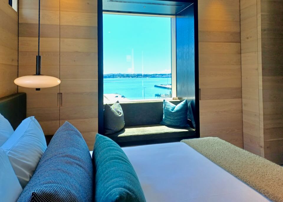 A hotel window nook has a view of a harbor.