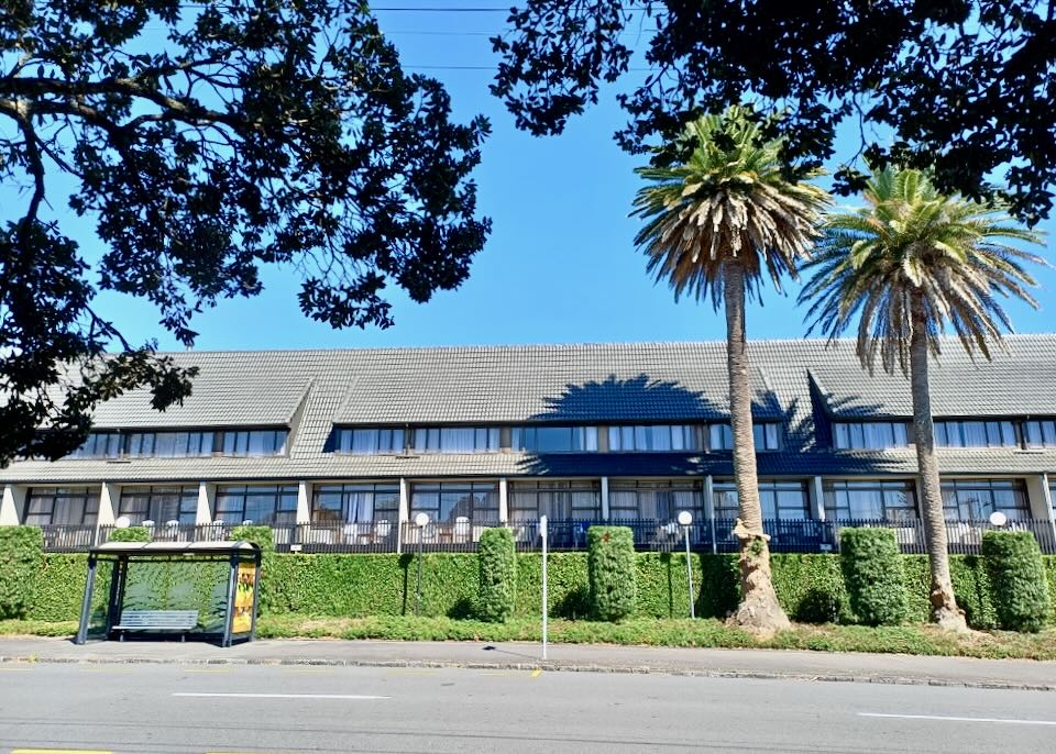 A short long building with palm trees.