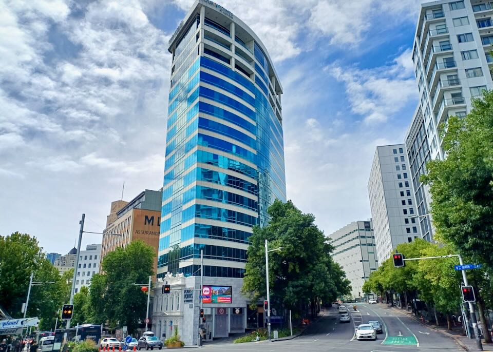 A tall blue windowed building sits at an intersection.