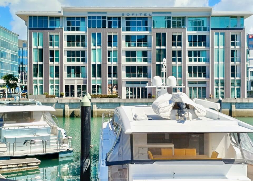 A hotel sits on the harbor while parked boats float in front of it.