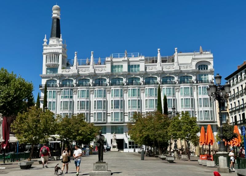 Large white hotel with a turret on a pedestrian square in Madrid