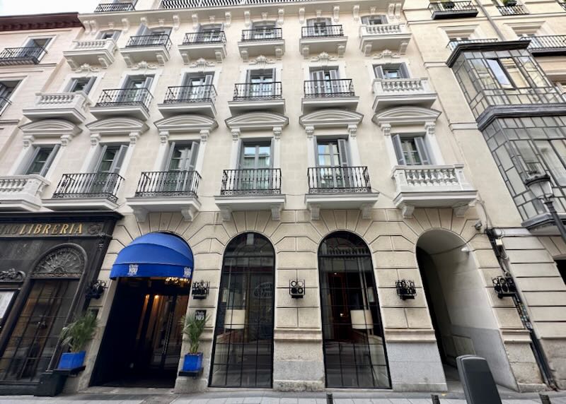 View looking up at an elegant white hotel with blue entrance awning