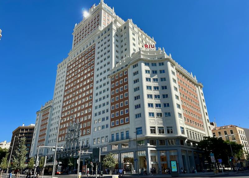 Looming high-rise hotel with the sun glinting off the top, against a backdrop of blue sky