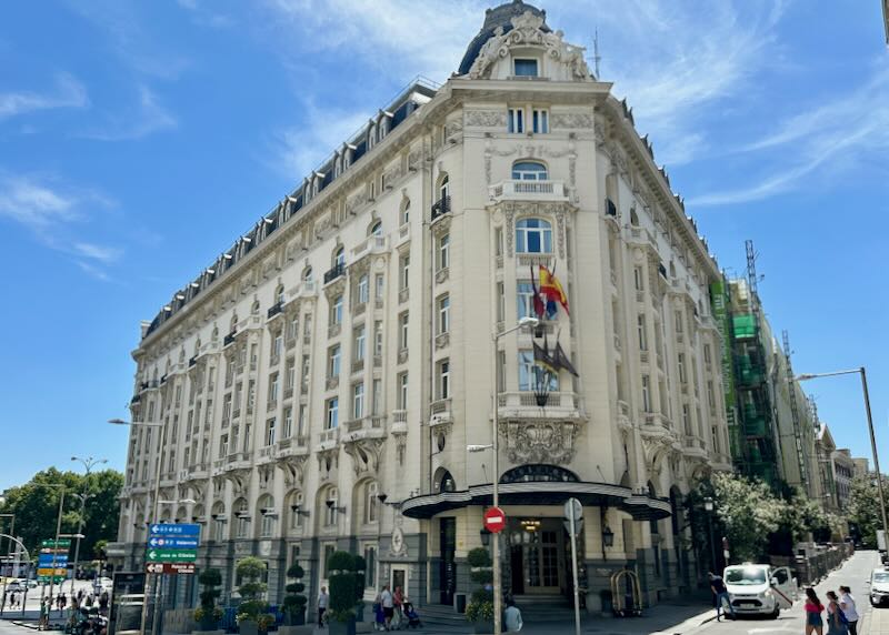 Corner view of an elegant white hotel on a busy Madrid street