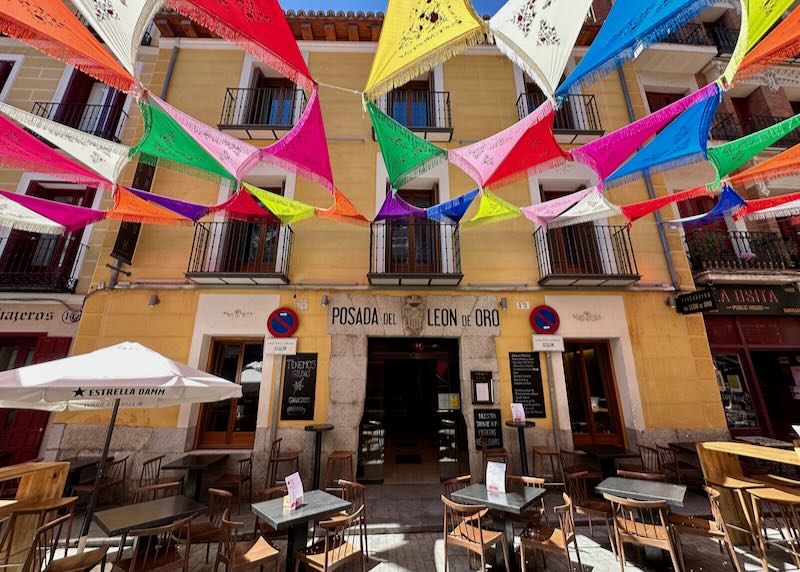 Small Spanish hotel with tables in front and colorful flags flying in front