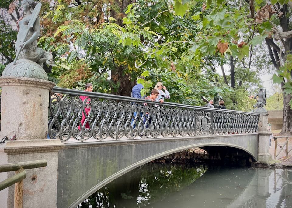 Kids look over a decorative footbridge into the water below.