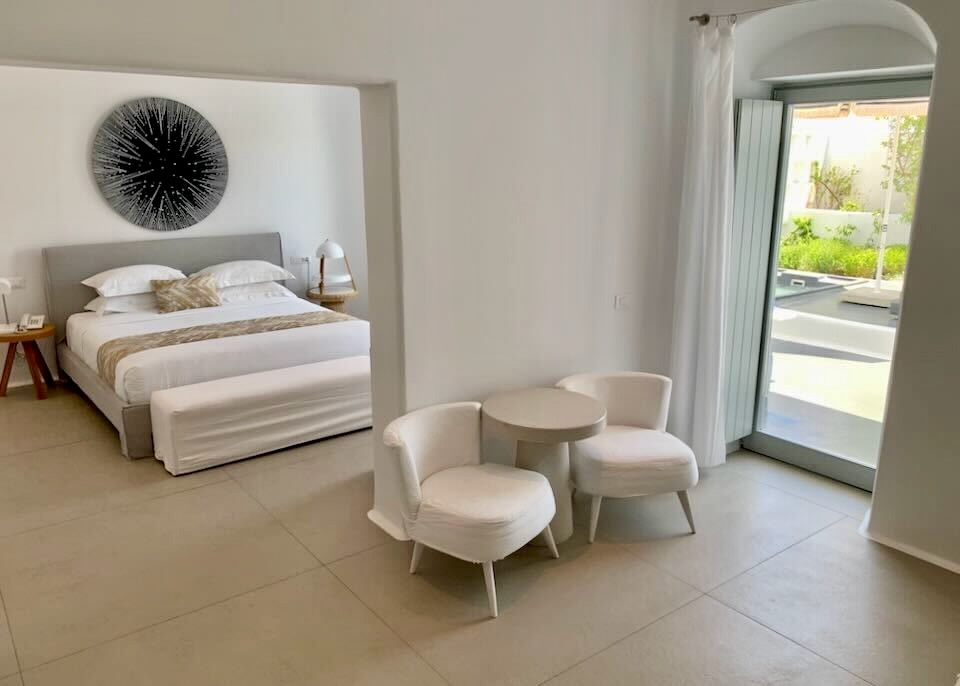 A sitting room leads back to a bedroom, while a side door leads to a terrace with private jacuzzi at Mykonos Blanc on Ornos Beach.