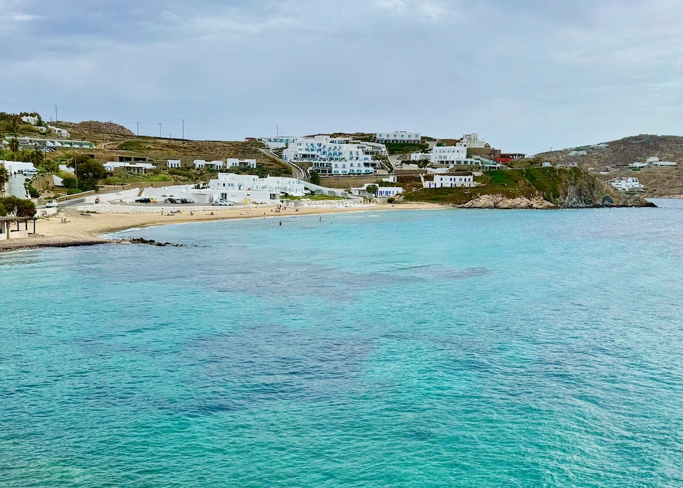 The sea spreading out in front of a beach with a low hill rising behind at Megali Ammos in Mykonos.