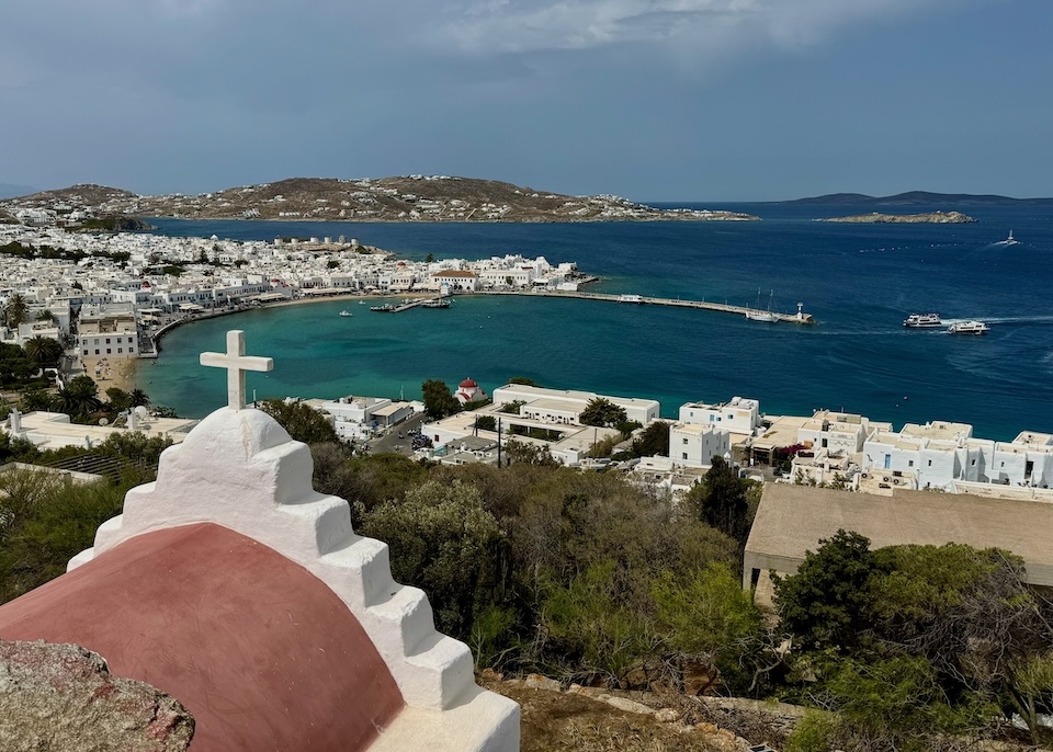 View from a red barrel-roofed church over the sea and Old Port neighborhood of Mykonos Town.