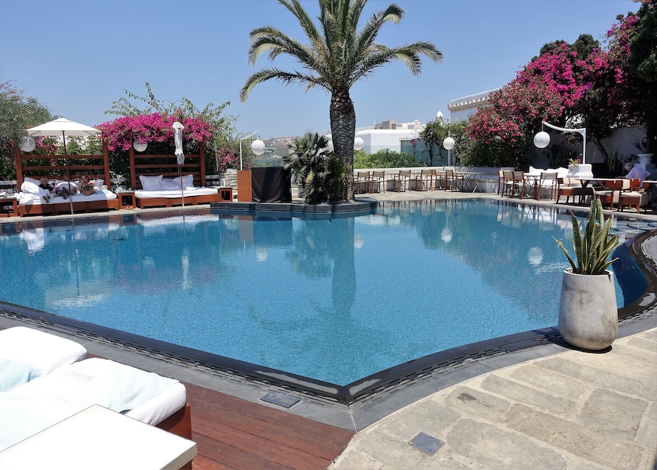 An infinity pool in a gardens setting with palm trees and bougainvilleas at Belvedere Hotel in Mykonos Town.