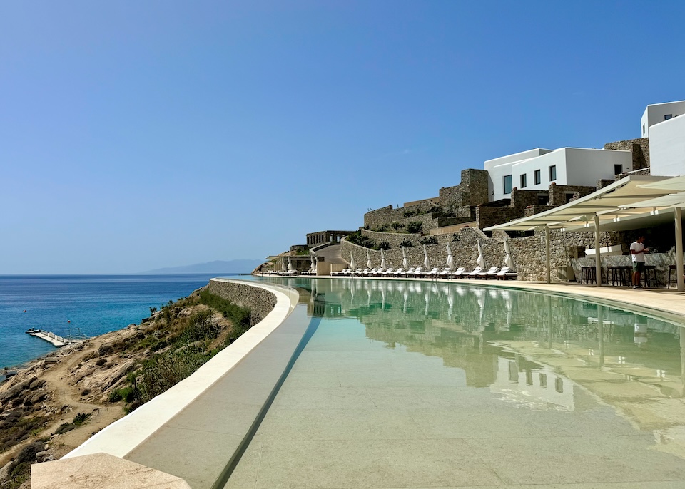 A gently curving pool stretches far into the distance on a hill above the sea at Cali Mykonos near Kalafatis Beach.