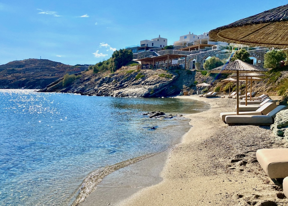 Pairs of sunbeds with thatched umbrellas stretch down the beach below Casa del Mar hotel in Aleomandra, Mykonos.