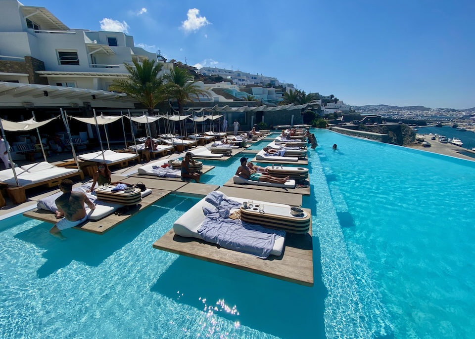 Two rows of floating sunbeds are suspended in an infinity pool above the sea in front of Cavo Tagoo hotel at the edge of Mykonos Town.