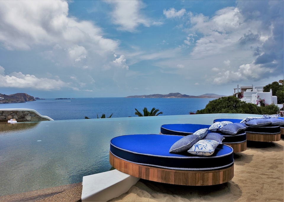 A row of circular sunbeds behind an infinity pool above the sea at Katikies Hotel in Agios Ioannis, Mykonos.