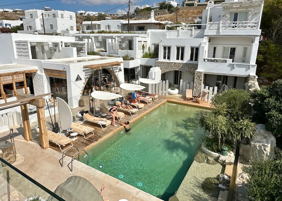 A rectangular pool set in a courtyard with a few sunbeds at Kensho Hotel in Ornos, Mykonos.