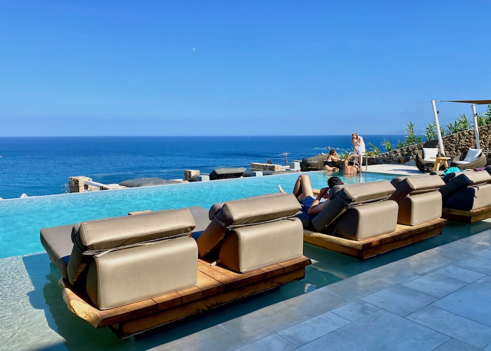 An infinity pool with pairs of sunbeds looking out to the sea at Mykonos Bliss in Kalo Livadi, Mykonos.