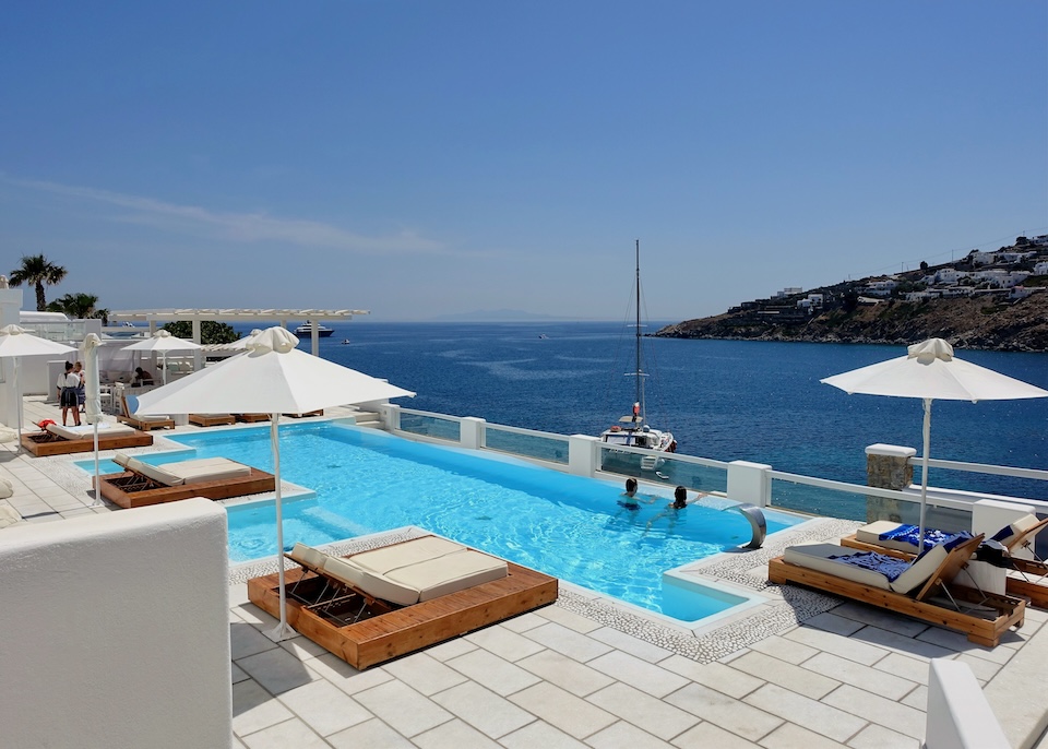 An infinity pool on a white marble sun terrace overlooking the sea at Nissaki hotel in Platis Gialos, Mykonos.