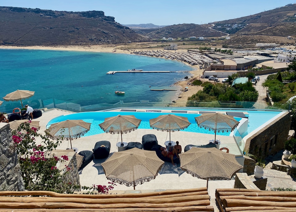 Macrame umbrellas sit behind an infinity pool above the beach at Panormos Village hotel in Panormos, Mykonos.