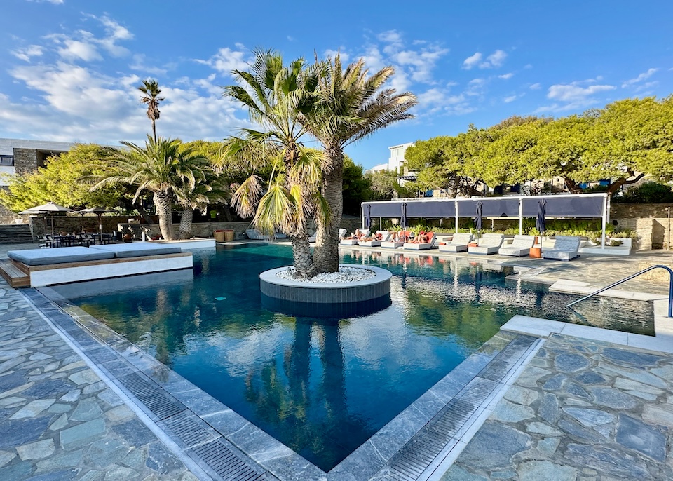 An island of palm trees sits in the middle of an infinity pool on a stone terrace at Mykonos Theoxenia hotel in Mykonos Town.