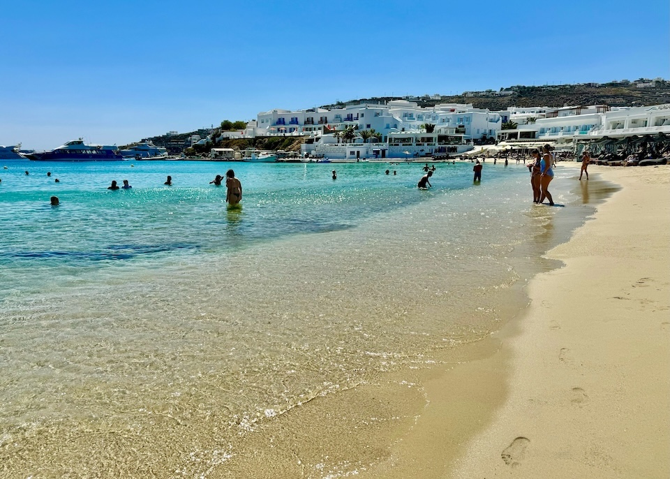 People swimming and wading at Platis Gialos Beach in Mykonos.