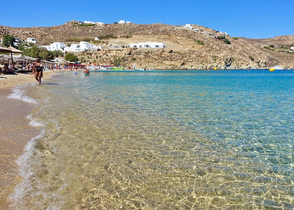 Crystal-clear water and golden sand at busy Super Paradise Beach in Mykonos.