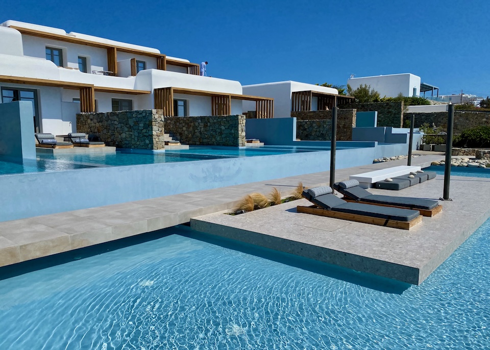 A terrace with private pools above a shared terrace with a pair sunbeds set above an infinity pool at Mykonos Soul in Agios Stefanos, Mykonos.