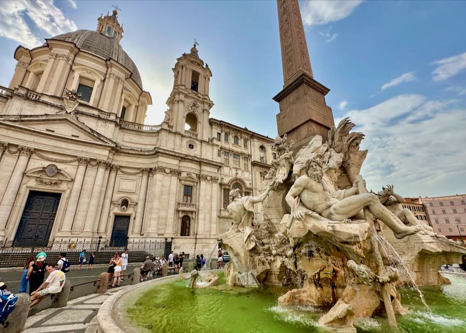 Close-up shot of the Neptune Fountain in Rome, with people sitting along the edge.