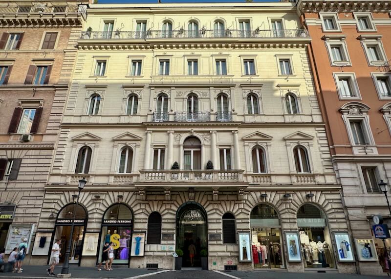 Exterior view of a Roman hotel with pedestrians walking by