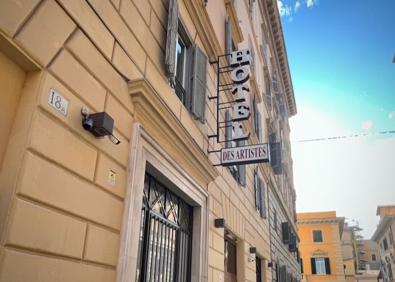 View looking up at a hotel sign on a Roman street