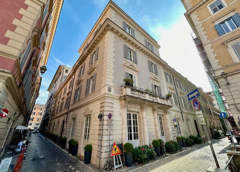 Corner view of a stone hotel building on narrow Roman streets