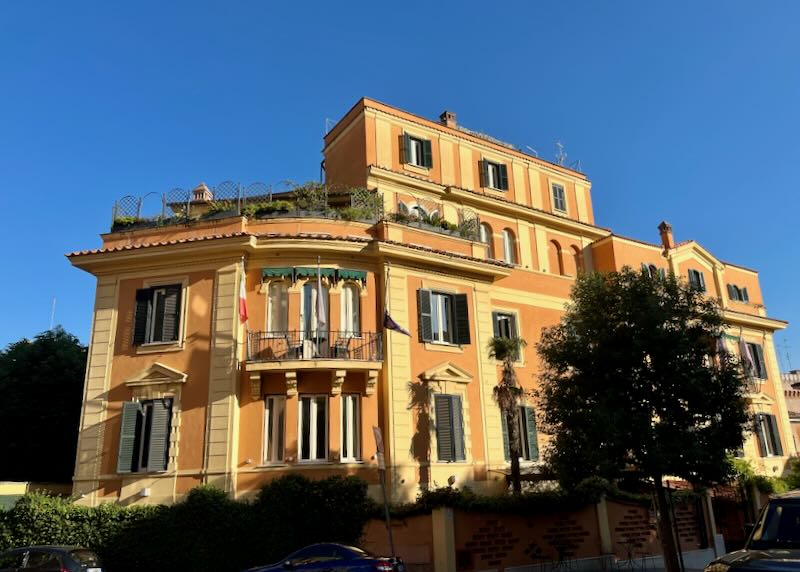 Corner view of a large salmon-colored Mediterranean hotel with the sun hitting it at sunset