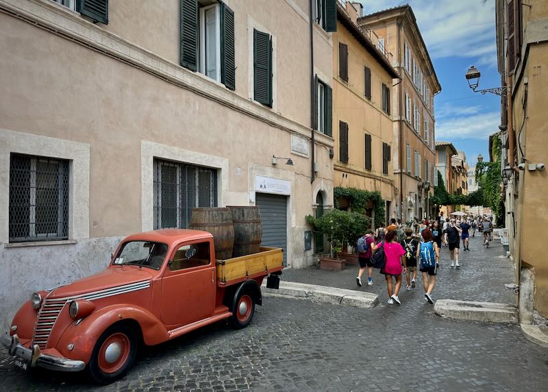 A narrow street in Trastevere, Rome, with an old red truck parked at the side