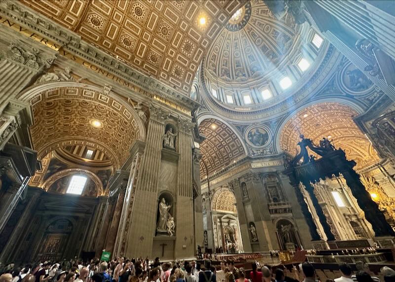 View looking up at the golden interior of the dome of St Peter's Basilica in the Vatican