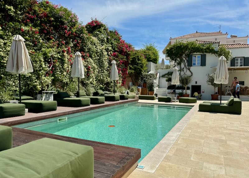 Hotel swimming pool surrounded by foliage and stuffed sun loungers