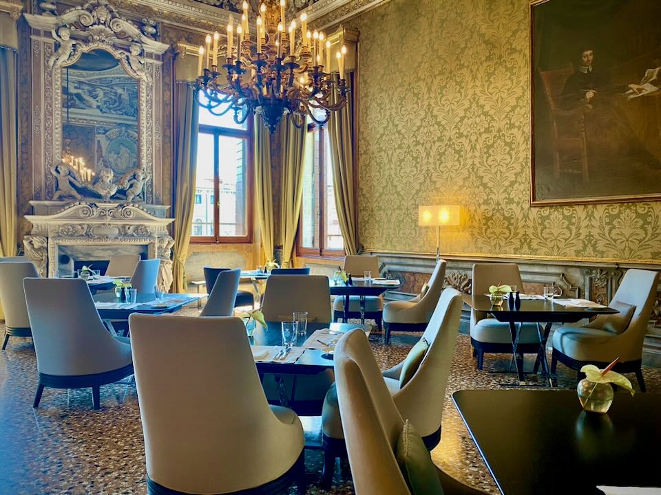 Elegant dining room with silk wallpaper, an elaborate fireplace, and glass chandelier