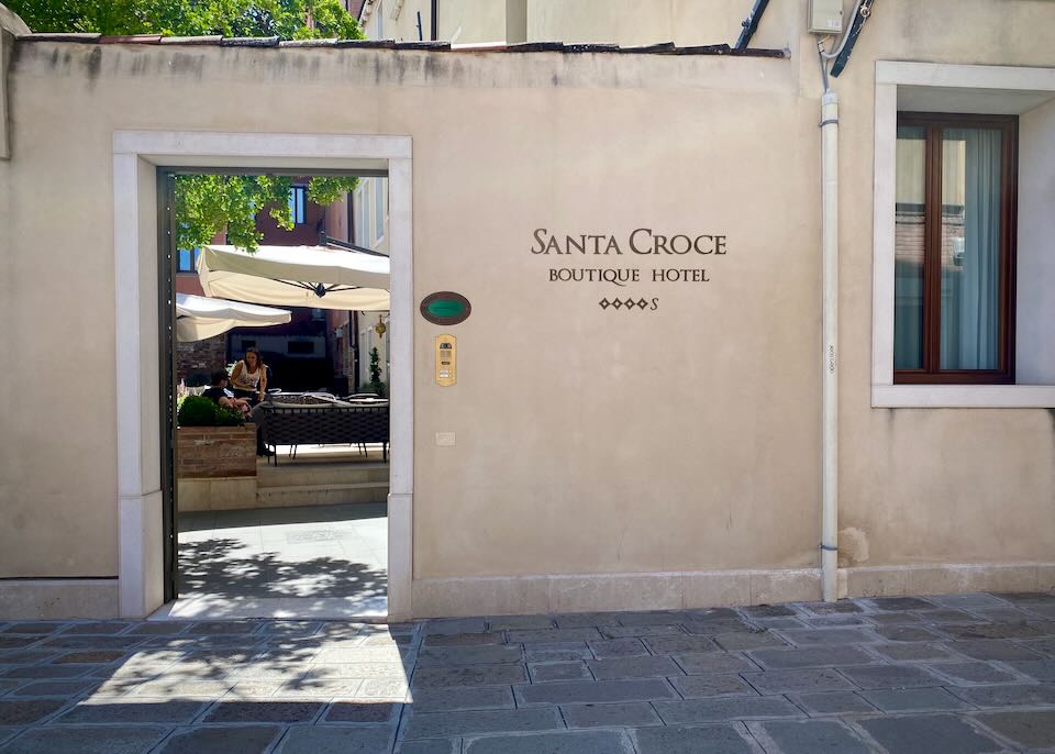 Looking in the doorway to a courtyard with umbrella-covered tables in Italy