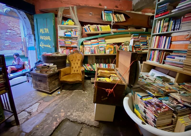 Small shop interior with books packed in boats and tubs from floor to ceiling