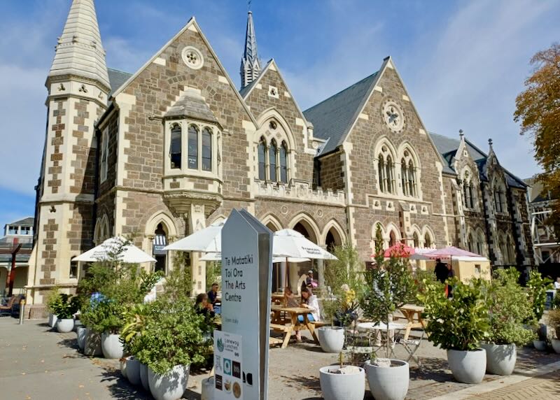 A castle-like brick building with tables and umbrellas outside.