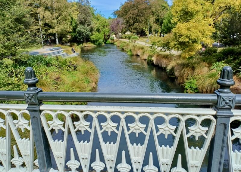 A white ornate metal railing protects walkers over a bridge.